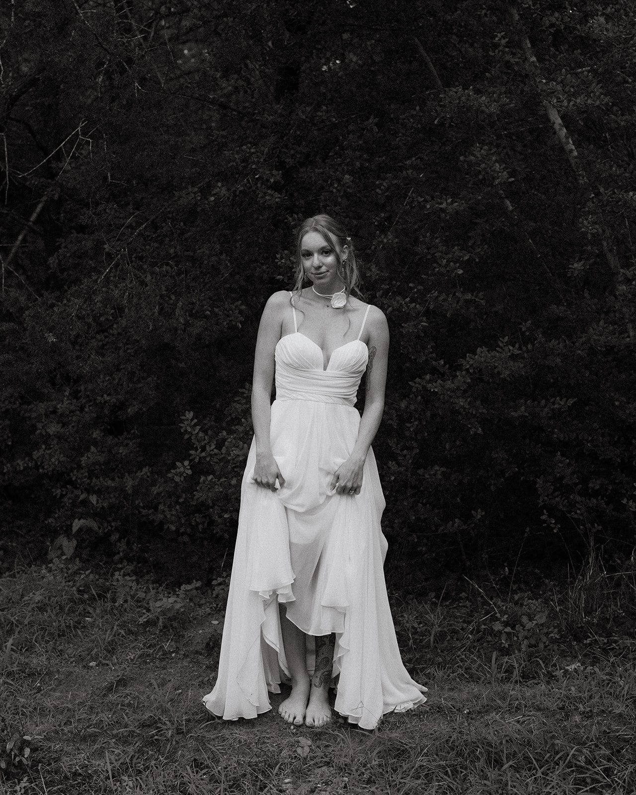 Portrait of your guide standing barefoot in a white dress among trees